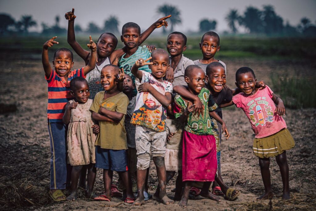 A joyful group of children happily pose together in a rural outdoor setting, expressing friendship and excitement.