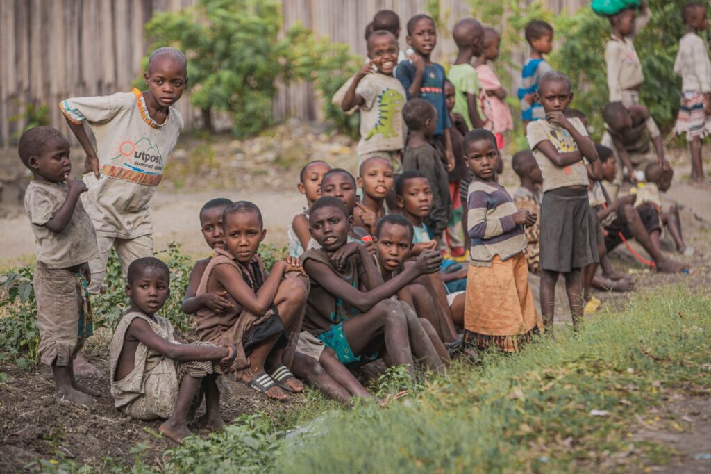 A group of children sitting and standing together outdoors, showcasing community and togetherness.