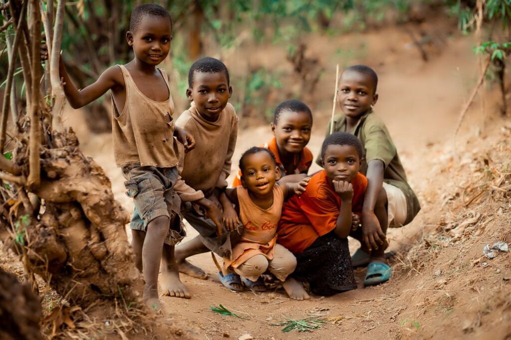 Group of smiling children posing together in a rural setting in Bujumbura, Burundi.