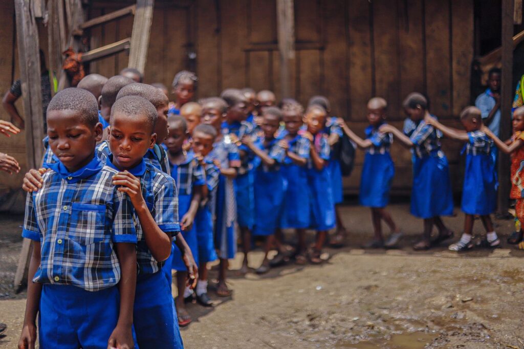 Group of school children in blue uniforms standing in a line outdoors.