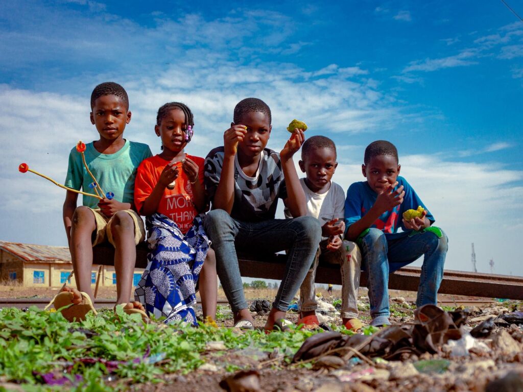 A group of children having fun outdoors in Kaduna, Nigeria, enjoying playtime under a bright sky.